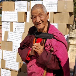 Alter Mönch dankt für die buddhistischen Bücher, die beim Monlam Chenmo verteilt wurden, Foto von Ed Palmer.
		
